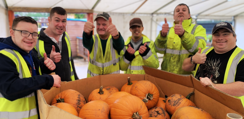 A picture of our students - all wearing hi-vis jackets standing around a pallet of pumpkins.