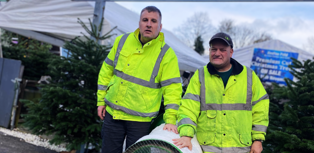 Two students stood either side of a Christmas Tree netter in hi-vis jackets.